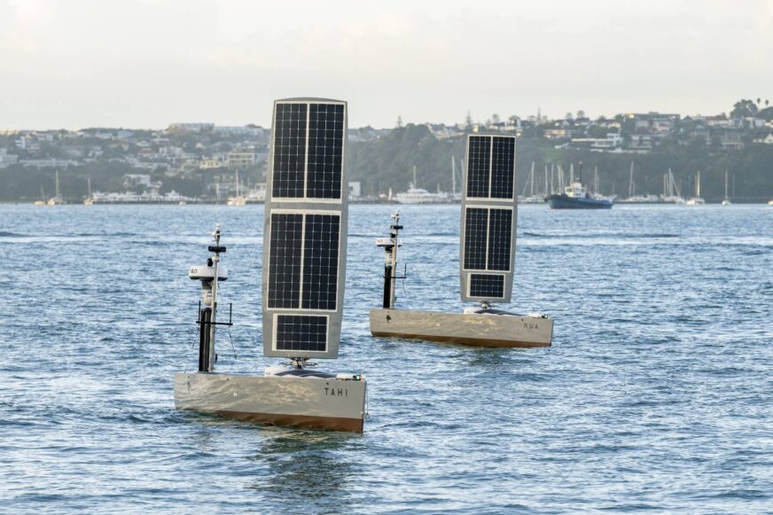Two Bluebottles USVs sit in the water near a harbour.
